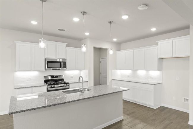 Kitchen with a sink, visible vents, wood finished floors, and stainless steel appliances | Image 16