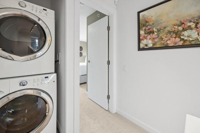 Washroom with stacked washing machine and dryer, light carpet, and baseboards | Image 31