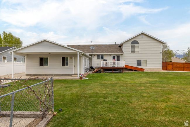 Back of property featuring a lawn, a fenced backyard, roof with shingles, and a deck | Image 49