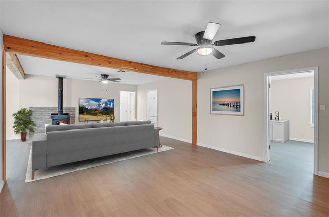 Living room featuring beamed ceiling, ceiling fan, wood-type flooring, and a wood stove | Image 14