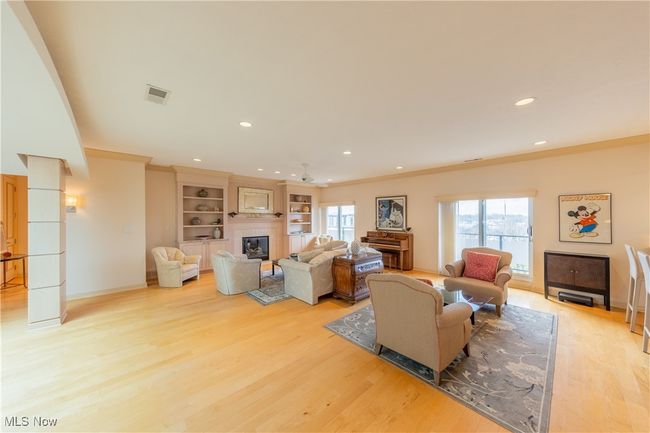 Living room with ornamental molding, light wood-type flooring, visible vents, and a glass covered fireplace | Image 13