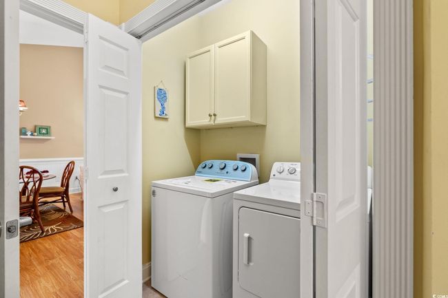 Washroom featuring cabinet space, washing machine and clothes dryer, and light wood finished floors | Image 20