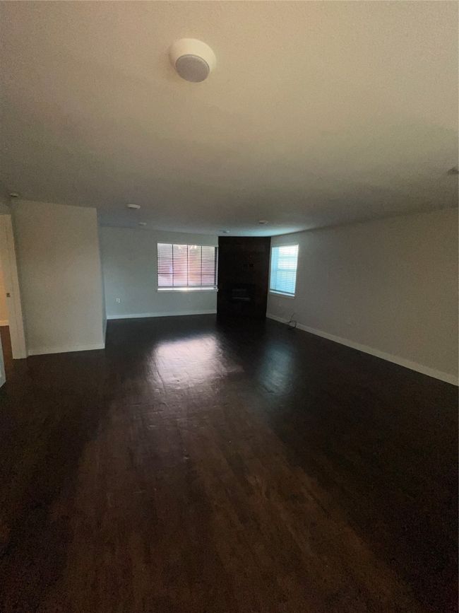Unfurnished living room featuring baseboards and dark wood-type flooring | Image 8