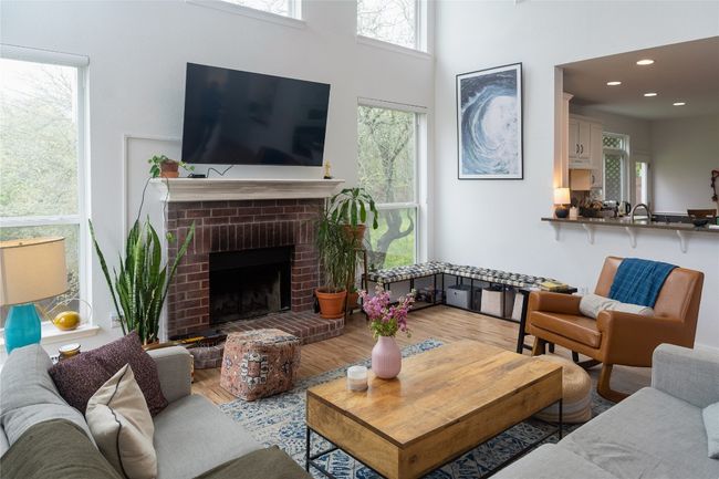 Living room featuring wood finished floors, a fireplace, and a towering ceiling | Image 9