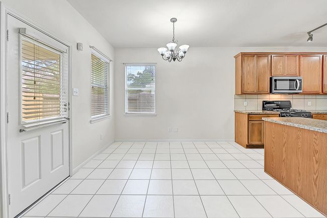 The breakfast table area is light and bright with two windows and a door to access the covered back patio. | Image 11
