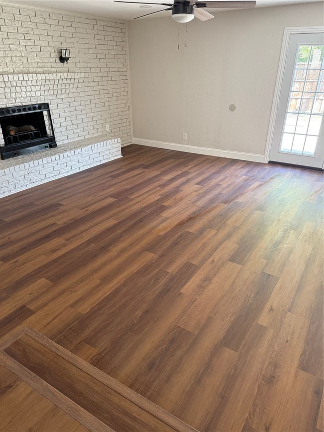 Unfurnished living room featuring ceiling fan, a fireplace, and dark wood-style flooring | Image 10