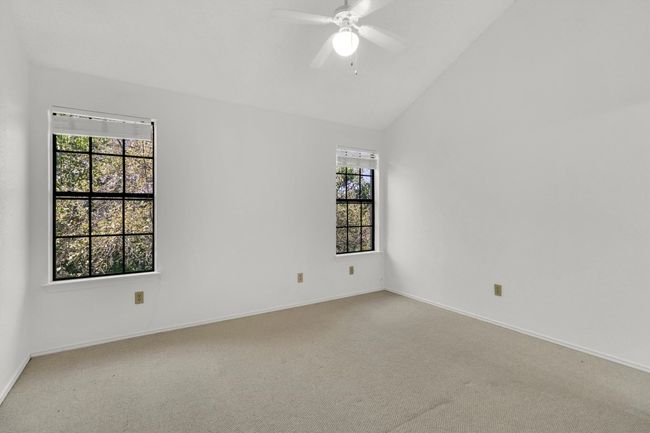 Spare room featuring baseboards, vaulted ceiling, carpet flooring, and a ceiling fan | Image 16