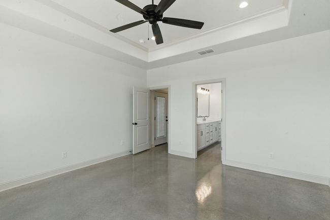 Spare room with a raised ceiling, concrete flooring, recessed lighting, baseboards, and ceiling fan | Image 11