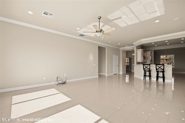 Empty room featuring crown molding, light tile patterned floors, ceiling fan, visible vents, and recessed lighting | Image 30