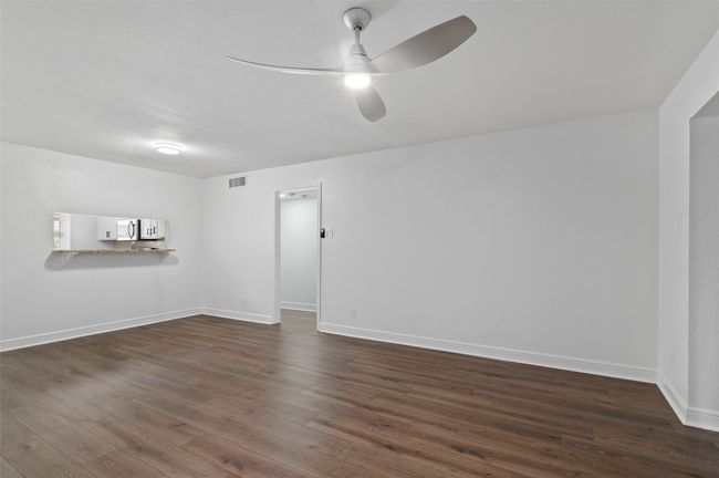 View from sliding doors back into living/dining area. Custom ceiling fan, passthrough window and brand new flooring. | Image 8