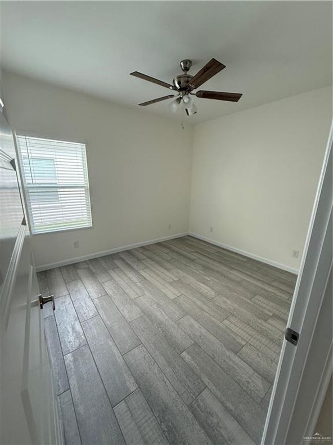 Empty room with wood finished floors, ceiling fan, and baseboards | Image 12