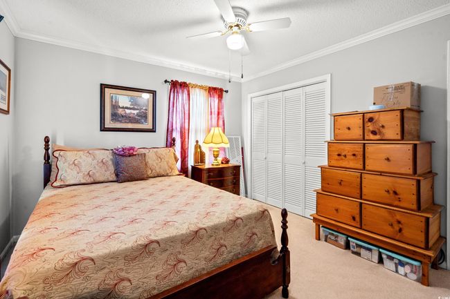 Carpeted bedroom with multiple closets, crown molding, and a ceiling fan | Image 30