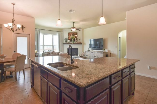 Kitchen featuring a brick fireplace, dishwasher, arched walkways, a sink, and ceiling fan with notable chandelier | Image 6