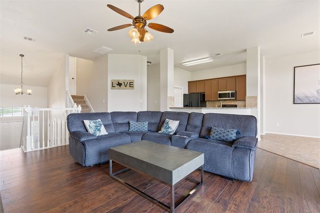 Living area featuring dark wood-style flooring, ceiling fan with notable chandelier, and visible vents | Image 24