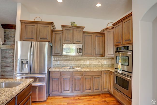 Kitchen featuring decorative backsplash, recessed lighting, light stone counters, and stainless steel appliances | Image 21