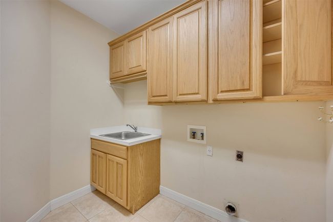 Washroom with electric dryer hookup, cabinet space, light tile patterned floors, and washer hookup | Image 27