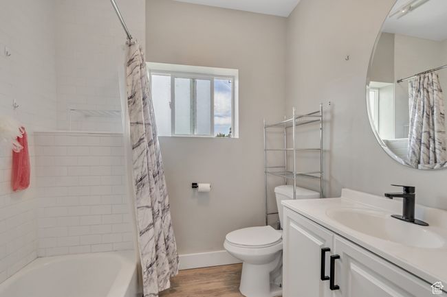 Full bath featuring wood finished floors, vanity, and shower / tub combo with curtain | Image 14