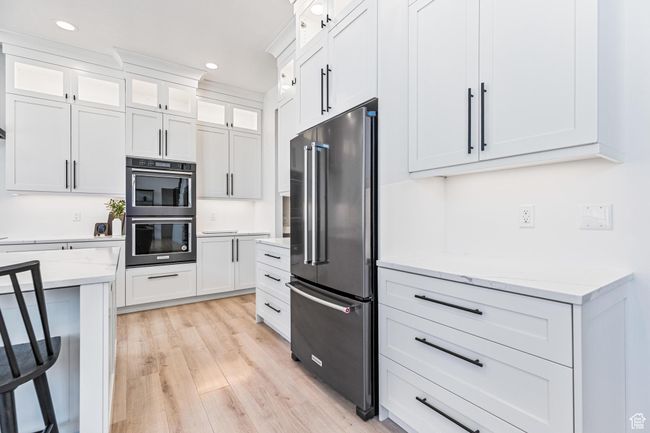 Kitchen featuring double wall oven, high end fridge, recessed lighting, white cabinetry, and light wood finished floors | Image 56