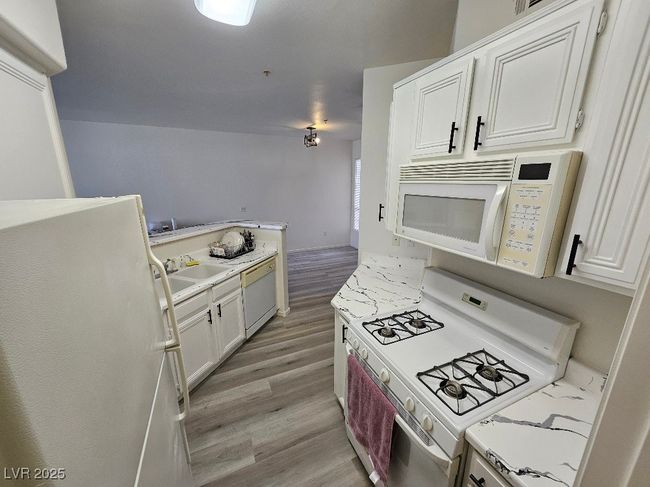 Kitchen featuring light wood-type flooring, light countertops, white appliances, and a sink | Image 26