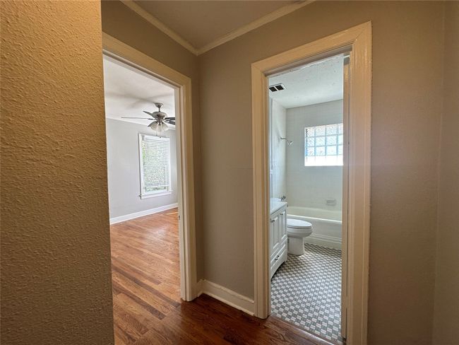 Hallway featuring dark wood finished floors, a textured wall, visible vents, crown molding, and baseboards | Image 6