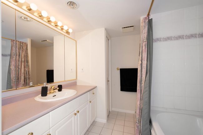 Full bathroom featuring vanity, shower / tub combo with curtain, baseboards, tile patterned floors, and visible vents | Image 30