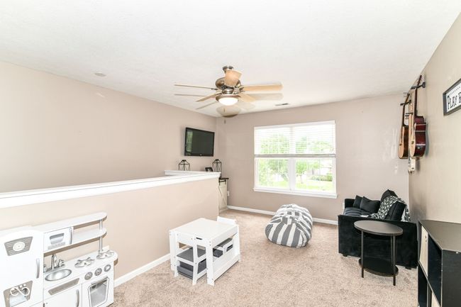 living area with carpet, a ceiling fan, and baseboards | Image 21