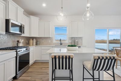 (Photo of a decorated model, actual homes finishes will vary) The stunning kitchen features a large center island, quartz countertops, LVP floors and stainless appliances! | Image 2