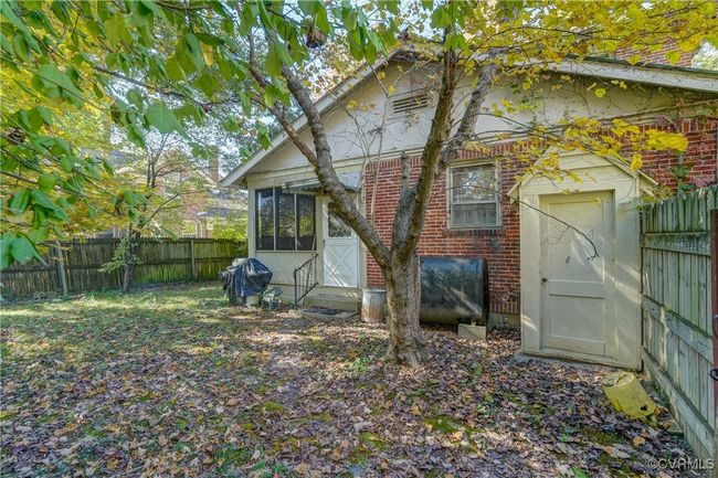 Rear view of house featuring brick siding, a sunroom, and fence | Image 27