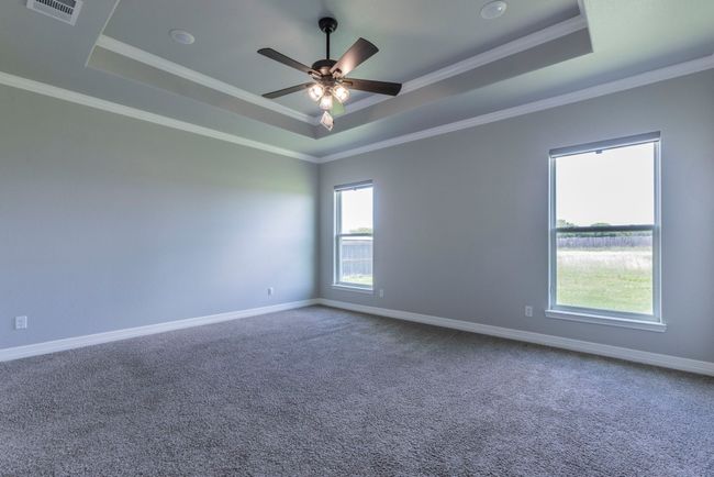 Unfurnished room featuring a raised ceiling, carpet, a ceiling fan, and crown molding | Image 12