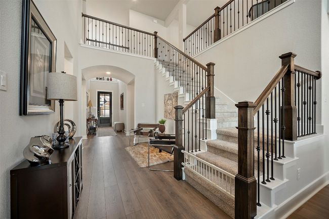 Entrance foyer with arched walkways, a towering ceiling, dark wood finished floors, and stairs | Image 13