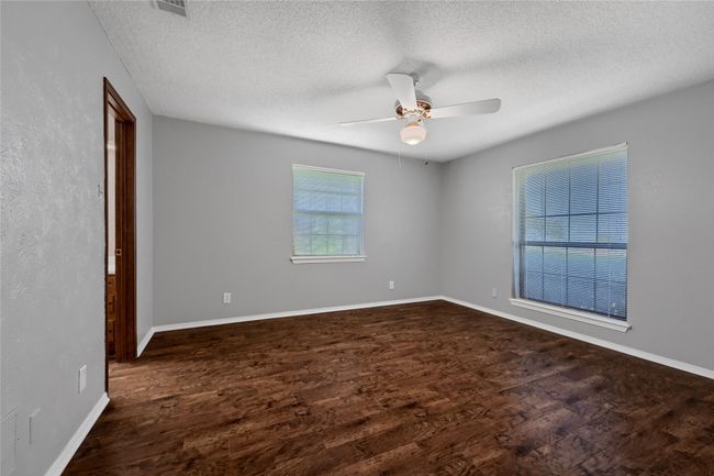 Unfurnished room featuring dark wood-type flooring, a textured ceiling, baseboards, and ceiling fan | Image 18