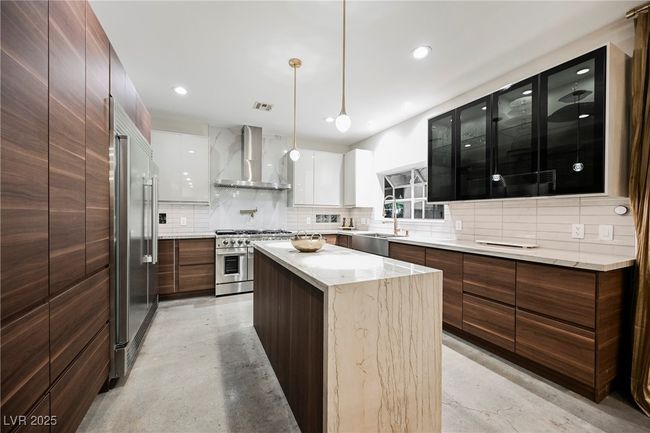 Kitchen featuring high quality appliances, wall chimney range hood, finished concrete flooring, modern cabinets, and a sink | Image 12