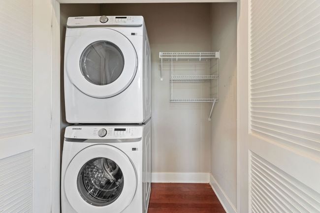Laundry area featuring stacked washer and dryer and dark wood finished floors | Image 16