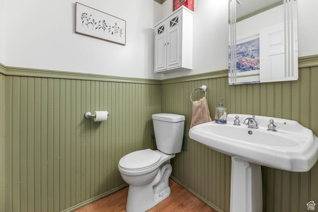 Half bathroom featuring a wainscoted wall, a sink, wood finished floors, and toilet | Image 21