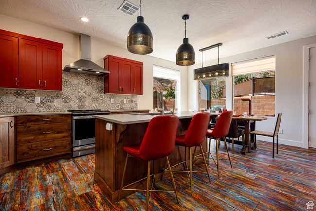 Kitchen with wall chimney range hood, a sink, and stainless steel electric stove | Image 12