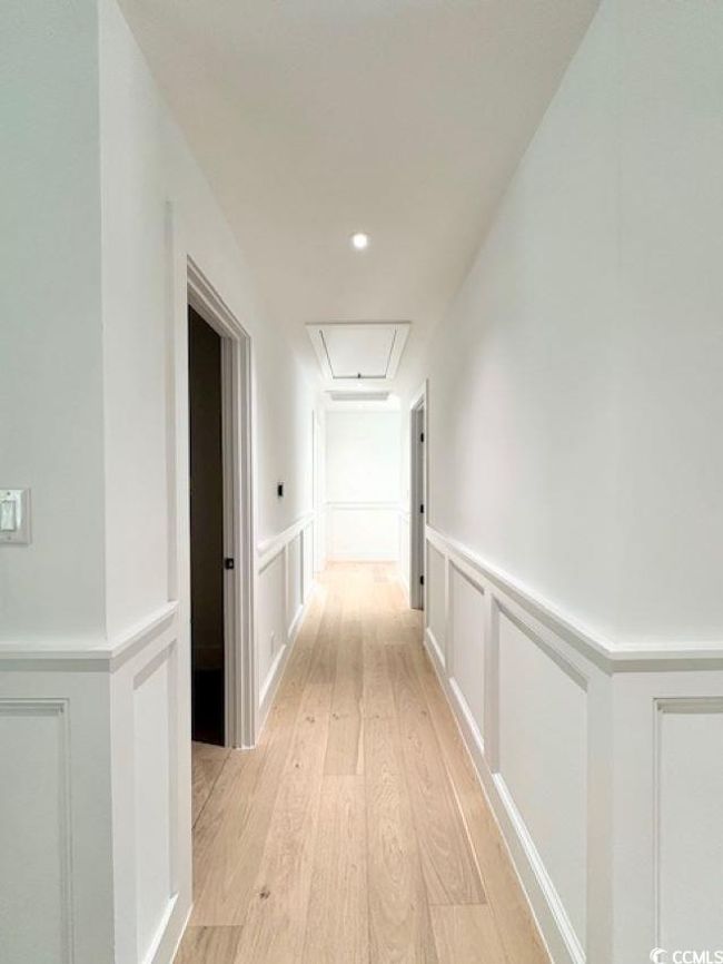Corridor featuring attic access, a decorative wall, light wood-type flooring, and wainscoting | Image 17