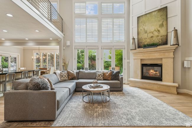 Living room with wood finished floors, a high ceiling, recessed lighting, a glass covered fireplace, and a chandelier | Image 10
