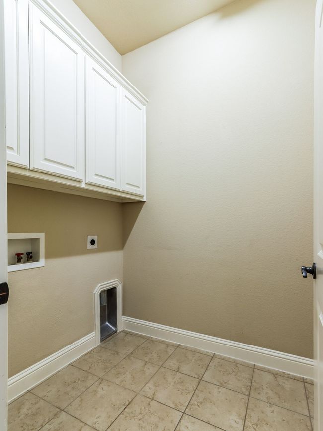 Laundry area featuring cabinet space, hookup for a washing machine, hookup for an electric dryer, and light tile patterned floors | Image 27