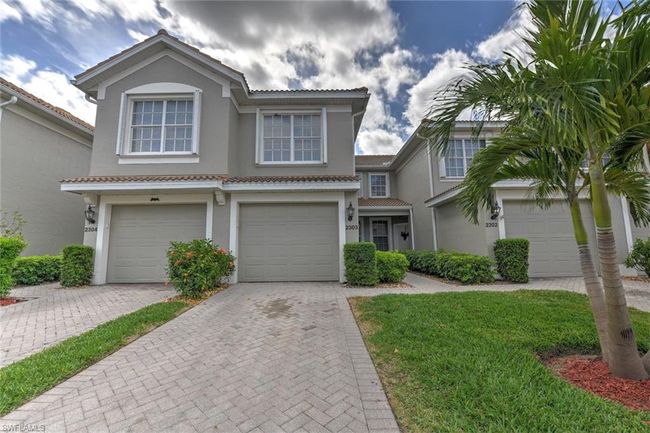 View of front facade with a tiled roof, stucco siding, driveway, and a garage | Image 4