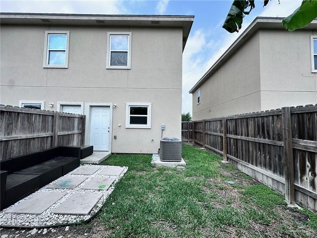 Rear view of property with central AC unit, stucco siding, a fenced backyard, and a yard | Image 11