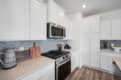 (Photo of decorated model, actual homes color and finishes will vary) Modern and functional, this kitchen is equipped with quartz kitchen countertops, subway tile backsplash, stainless steel appliances including the fridge and LVP flooring. | Image 3