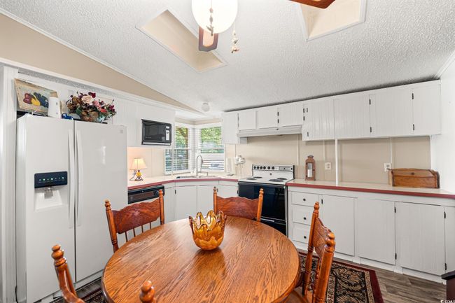 Kitchen with white refrigerator with ice dispenser, electric range oven, a textured ceiling, under cabinet range hood, and light countertops | Image 22
