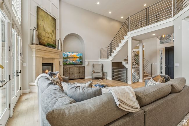 Living room with stairway, a high ceiling, a glass covered fireplace, recessed lighting, and french doors | Image 12