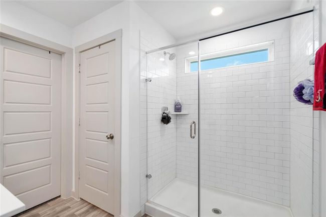 Walk-in shower with floor-to-ceiling subway tile, glass enclosure, and a large picture window for natural light. | Image 9