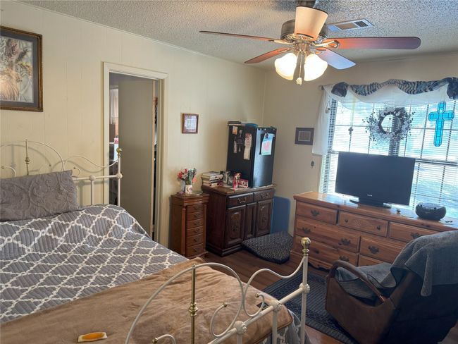 Bedroom with hardwood / wood-style floors, ceiling fan, and a textured ceiling | Image 11