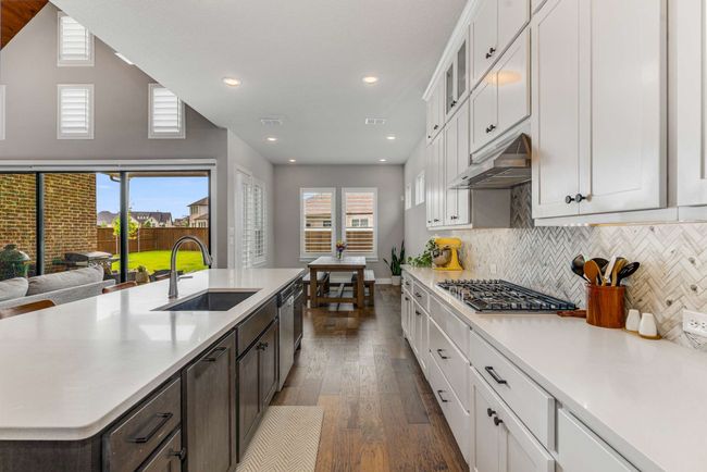 Sleek and modern with warm accents like wood flooring and herringbone backsplash! | Image 9