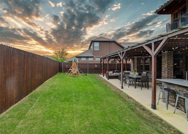 View of fenced backyard with extended covered patio, outdoor kitchen and entertainment area | Image 17