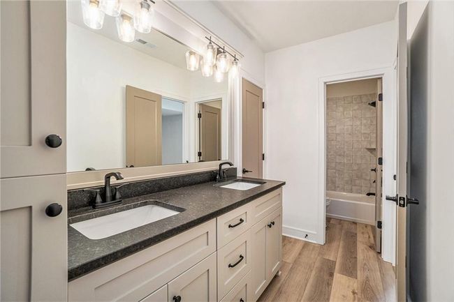 Bathroom featuring double vanity, wood finished floors, and shower / tub combination | Image 48