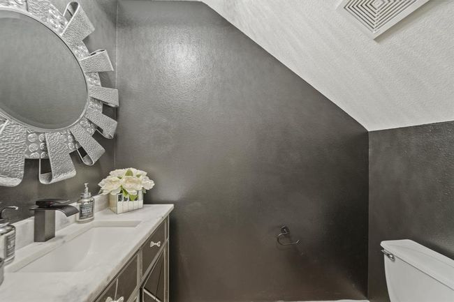 The elegant half bath features a dramatic accent wall, a mirrored vanity with marble countertop, and modern lighting, offering a touch of glam for your guests. | Image 24