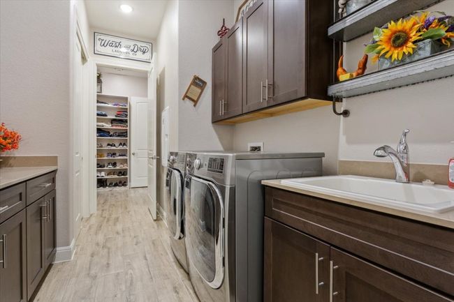 Laundry area featuring lots of cabinet space, sink, & wood look tile flooring | Image 29